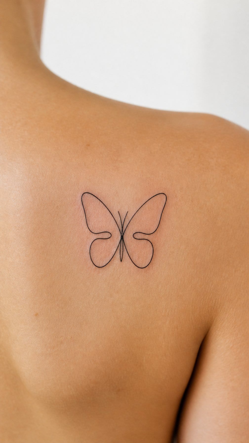 A minimalist butterfly tattoo formed from one continuous line on skin.