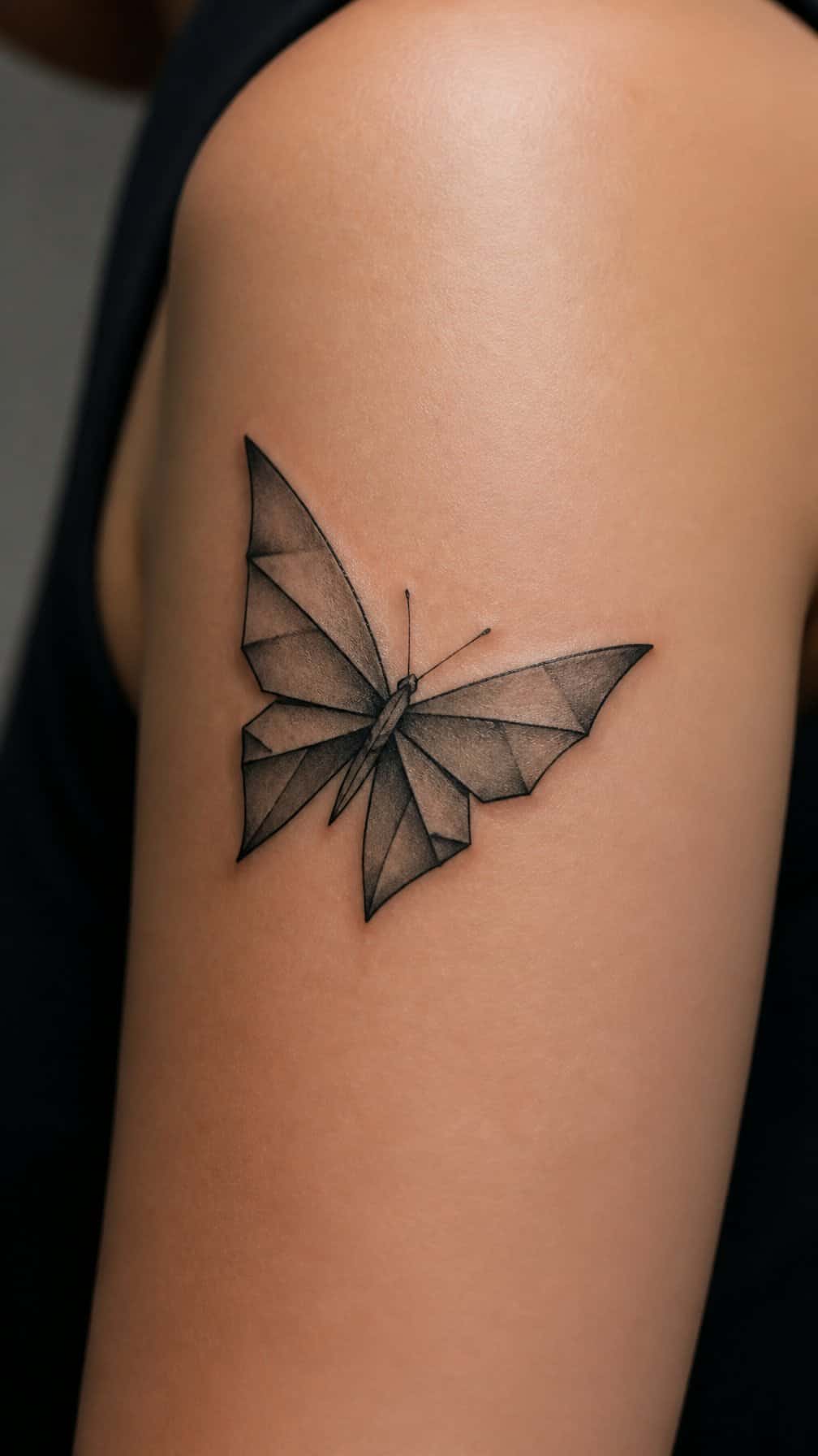 A geometric origami-style butterfly tattoo on skin.